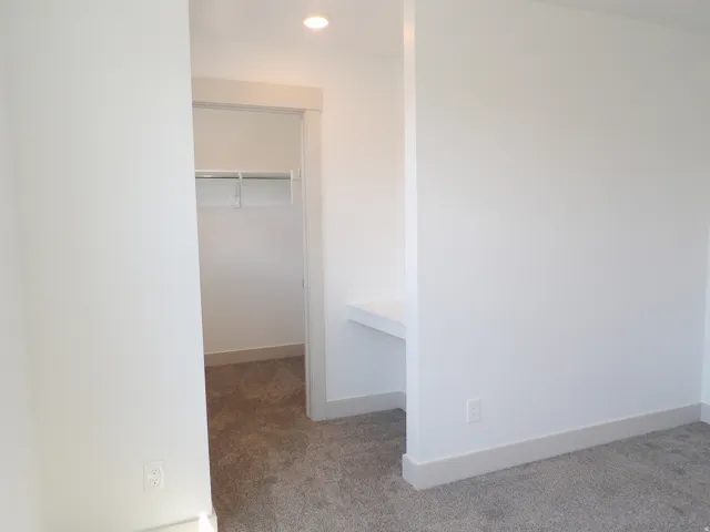 Built-in closet with hanging rod, recessed lighting, and a built-in desk area