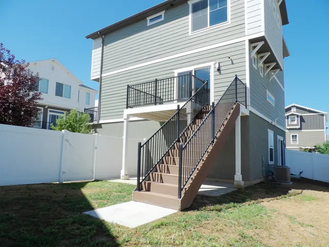Rear exterior featuring a multi-level deck, composite stairs with metal railings, and a fenced yard