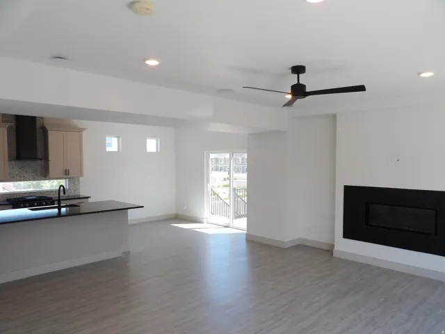 Open-concept living area with wood-finish flooring, recessed lighting, and a modern ceiling fan