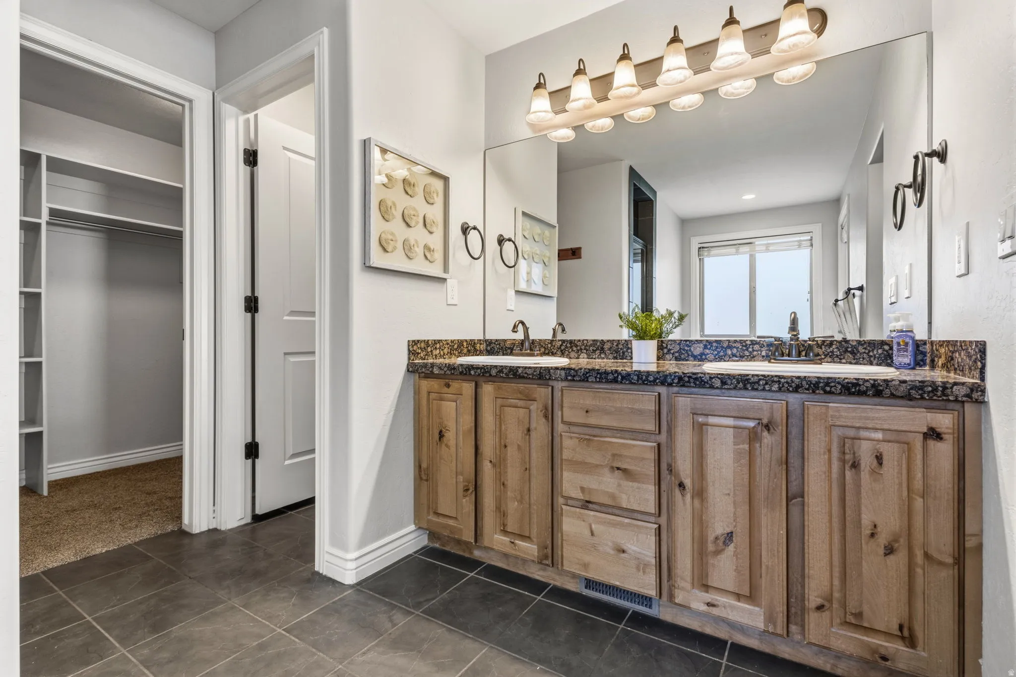 Dual vanity with integrated sinks, wood-finish cabinetry, and dark countertop
