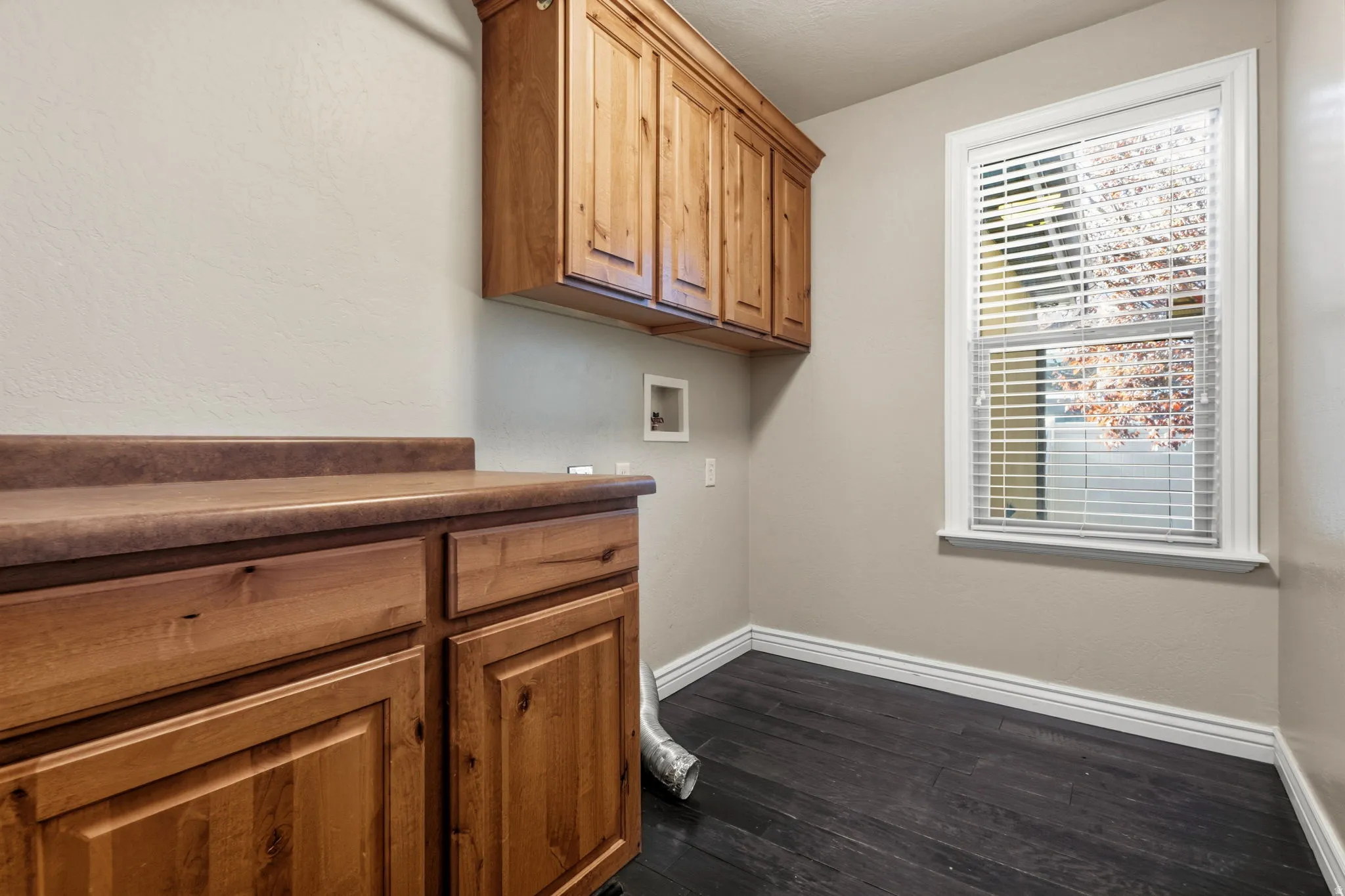 Wood-finish cabinetry with a contrasting countertop, wood-finish flooring, and natural light