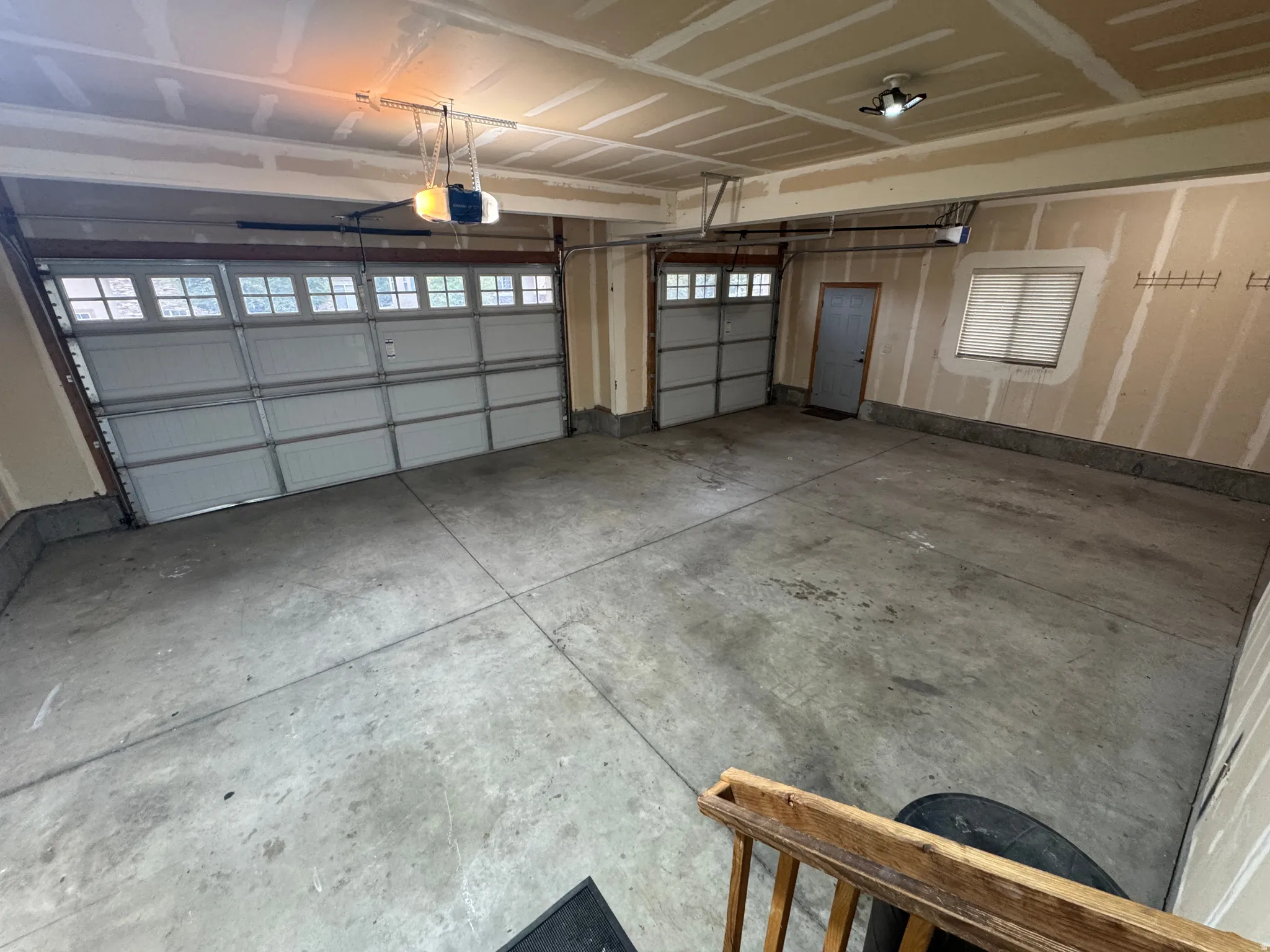 Two overhead garage doors with window inserts, concrete flooring, and an interior access door