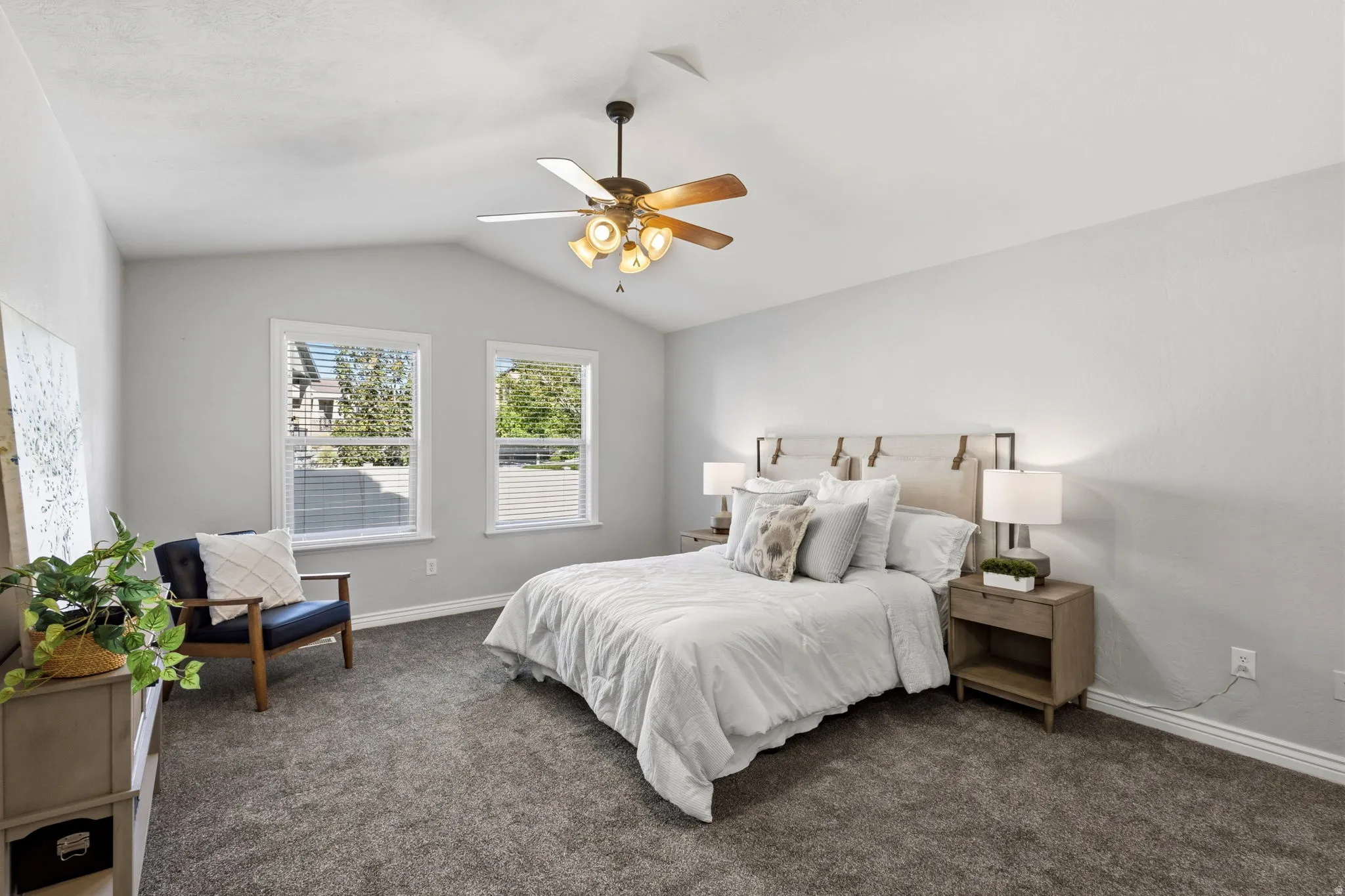 Vaulted ceiling featuring a ceiling fan, two double-hung windows, and wall-to-wall carpeting