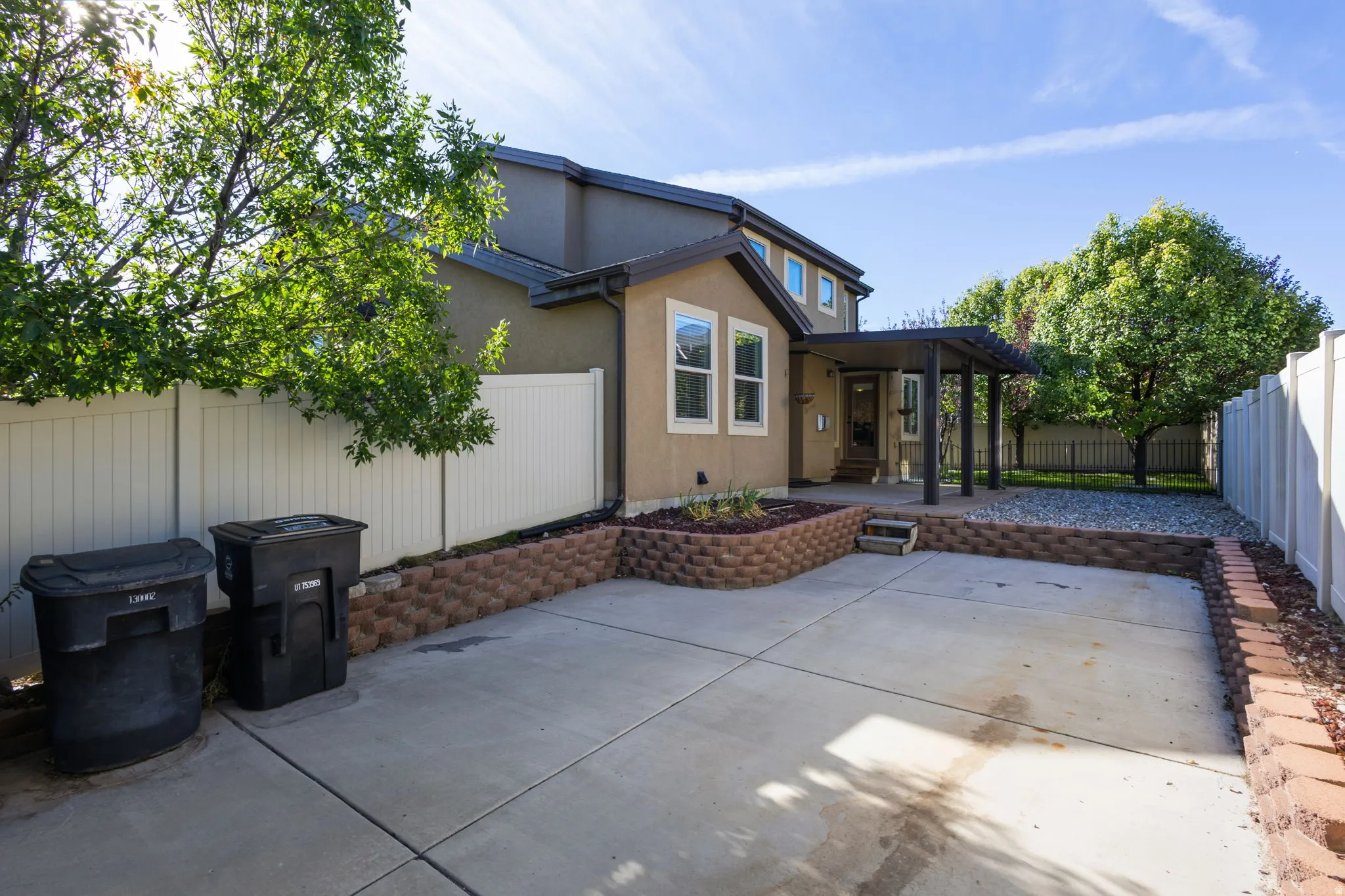 Concrete patio with an attached pergola and raised garden beds