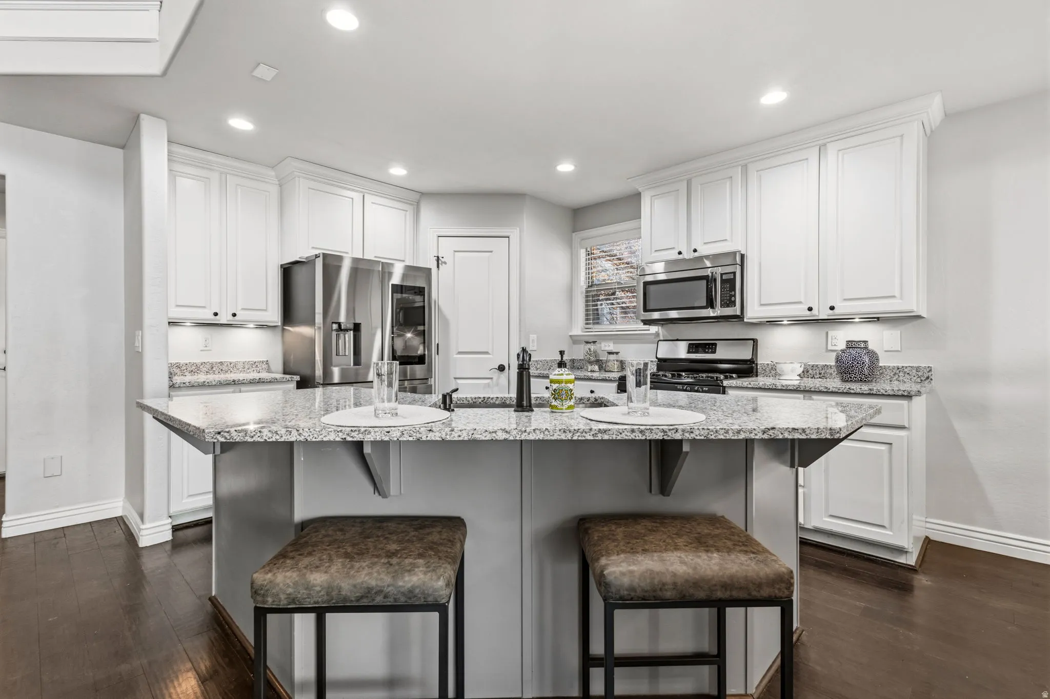 Kitchen featuring white cabinetry, light-toned countertops, recessed lighting, and stainless steel appliances