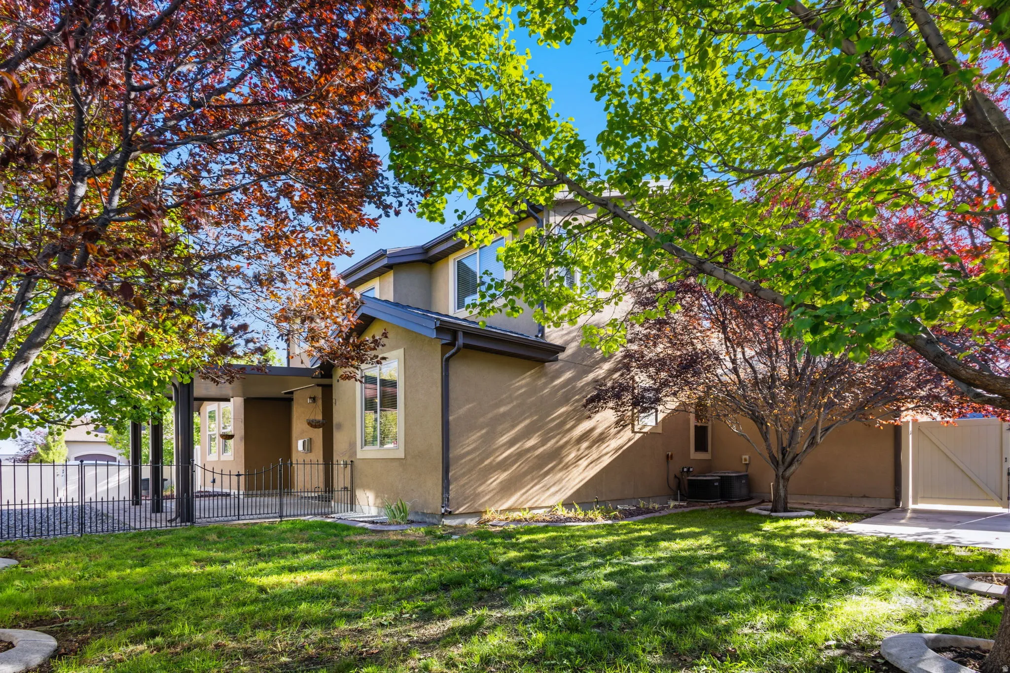Stucco exterior with multiple windows, covered entry, and black metal fencing