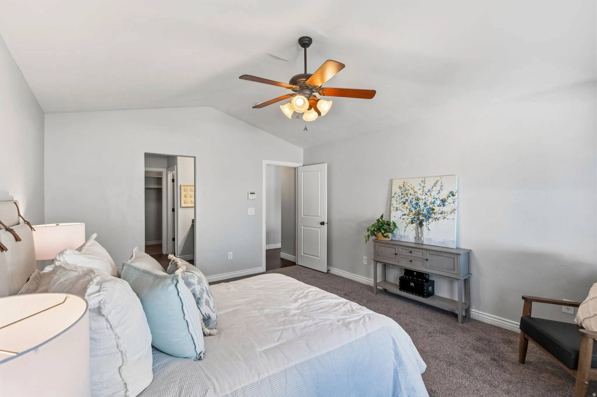 Carpeted flooring, vaulted ceiling, ceiling fan with light fixture, white interior doors, and a built-in closet