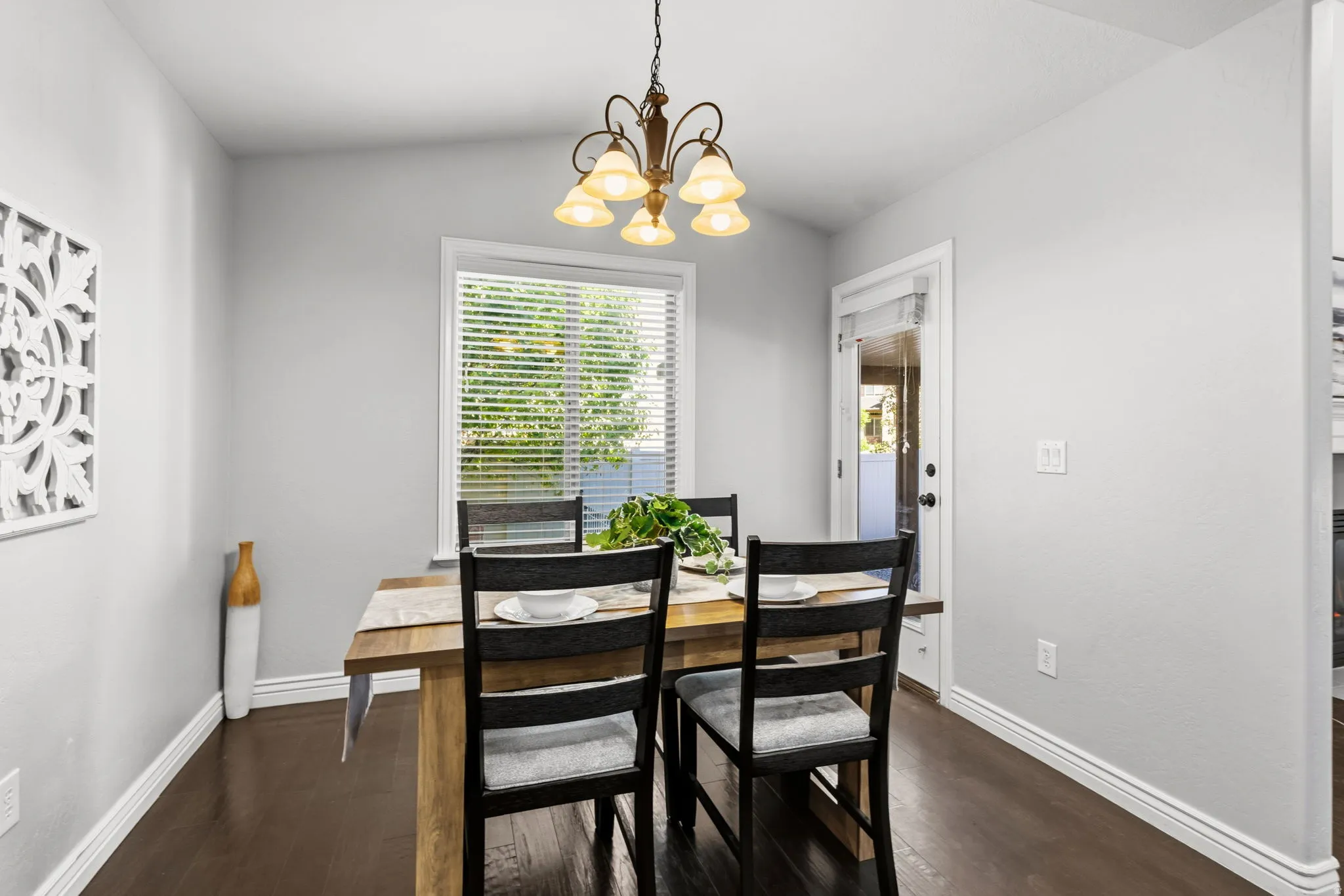Dining space featuring a wood-finish flooring, a window with blinds, and an overhead chandelier