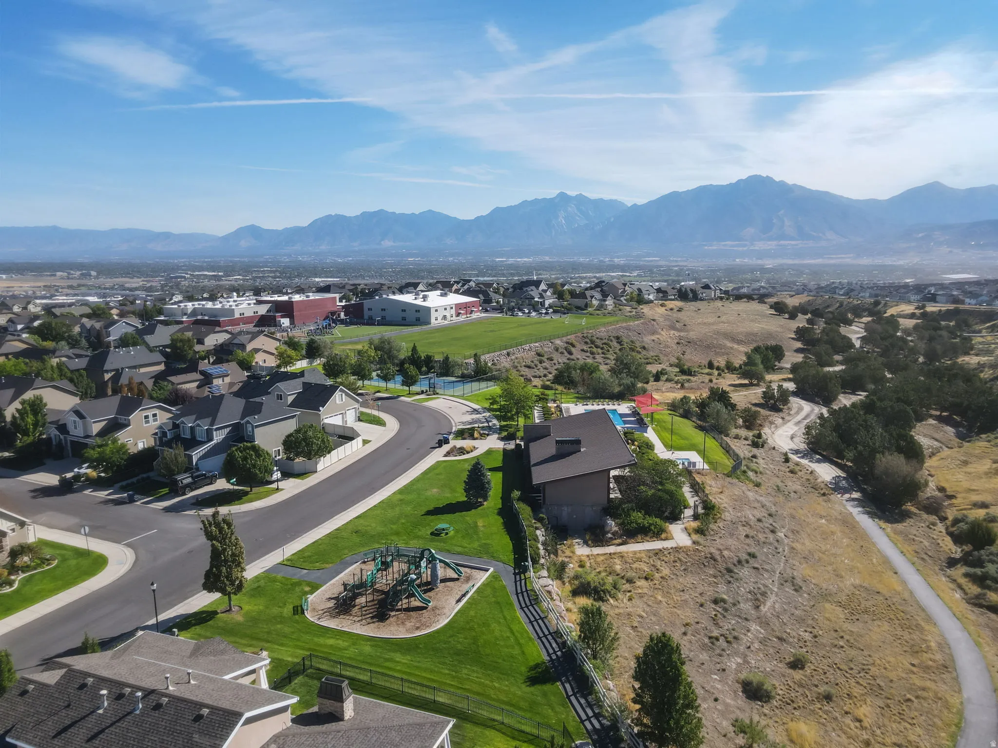 Mountain backdrop with expansive community amenities including a playground, tennis court, and swimming pool