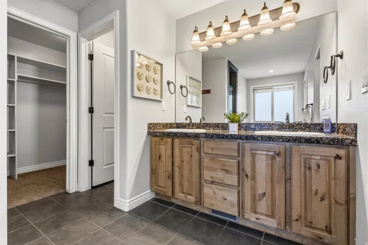 Dual vanity with integrated sinks, wood-finish cabinetry, and dark countertop