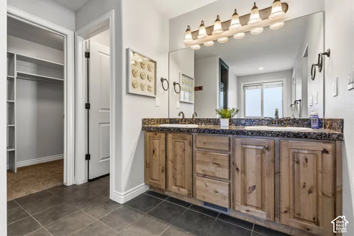 Dual vanity with integrated sinks, wood-finish cabinetry, and dark countertop