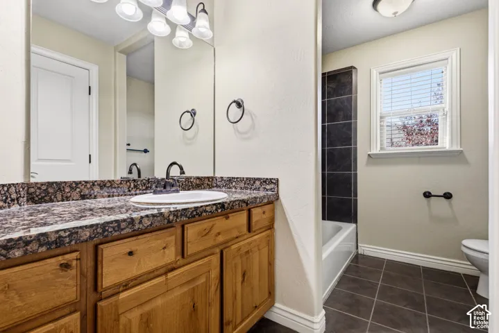 Bathroom vanity with a dark granite-style countertop and wood-finish cabinetry