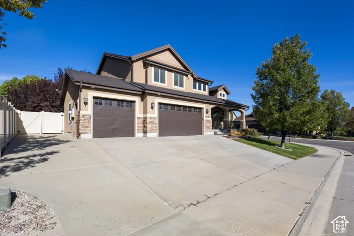 Stucco exterior with stone accents, attached two-car garage, covered entry, and a paved driveway