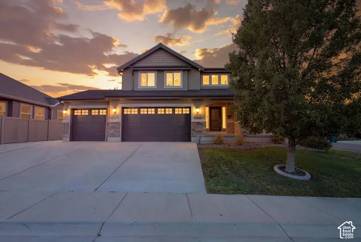 Two-story exterior with stone accents, an attached two-car garage, concrete driveway, and a manicured lawn
