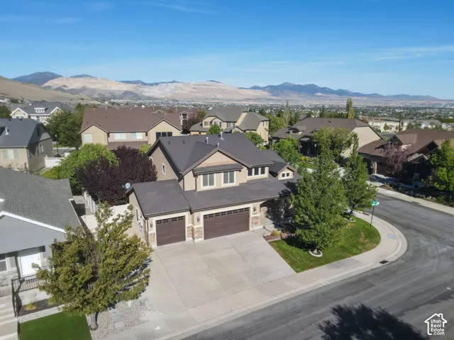 Multi-level residence featuring a dark shingle roof, light-toned stucco exterior, and a three-car garage