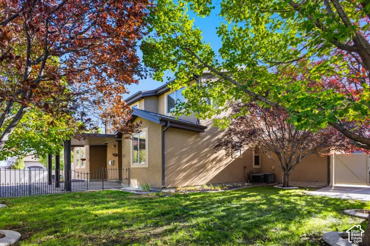 Stucco exterior with multiple windows, covered entry, and black metal fencing