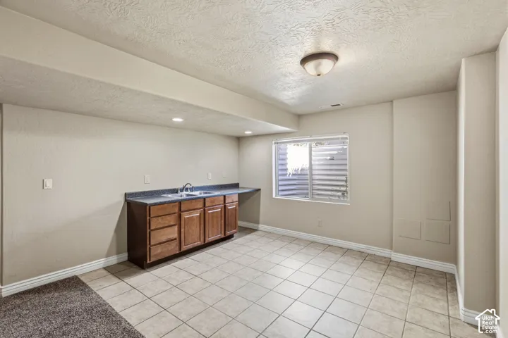Built-in cabinetry with a dual basin sink, dark countertop, and tiled flooring