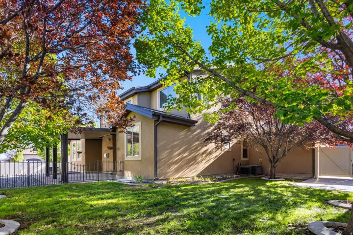 Stucco exterior with multiple windows, covered entry, and black metal fencing