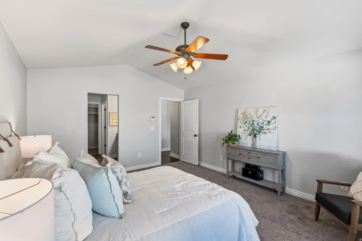 Carpeted flooring, vaulted ceiling, ceiling fan with light fixture, white interior doors, and a built-in closet