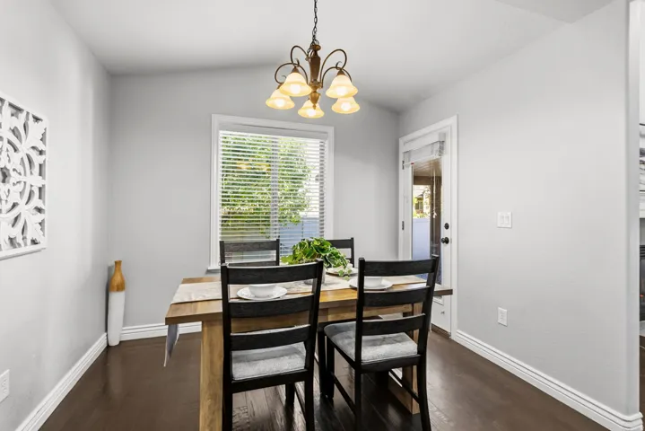 Dining space featuring a wood-finish flooring, a window with blinds, and an overhead chandelier