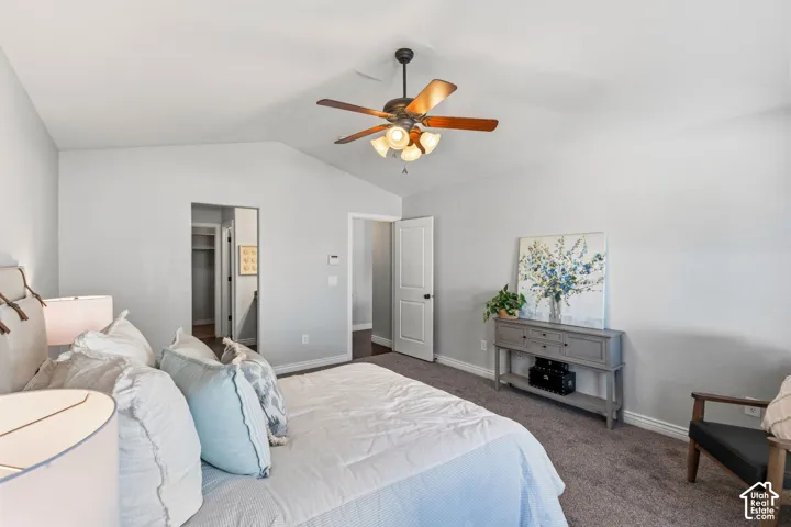 Carpeted flooring, vaulted ceiling, ceiling fan with light fixture, white interior doors, and a built-in closet