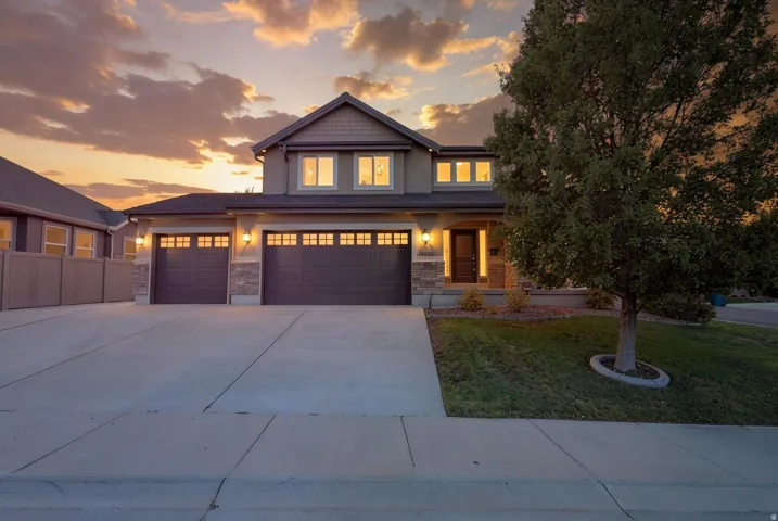 Two-story exterior with stone accents, an attached two-car garage, concrete driveway, and a manicured lawn
