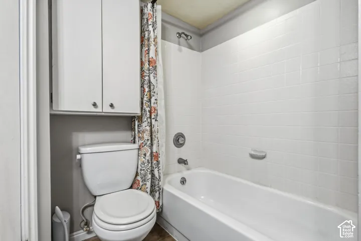 White subway tile tub surround, white bhttps://www.utahrealestate.com/lip/photo/listno/2182378#athtub, chrome shower fixtures, white over-toilet cabinetry, and wood-finish flooring