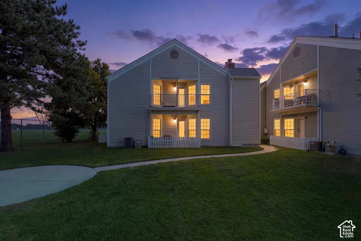 Two-story exterior with siding, individual balconies, separate patio areas, and a concrete pathway