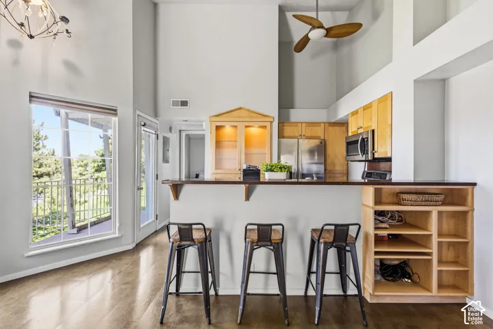Kitchen area featuring a breakfast bar with built-in shelving, wood-finish flooring, and a stainless steel refrigerator