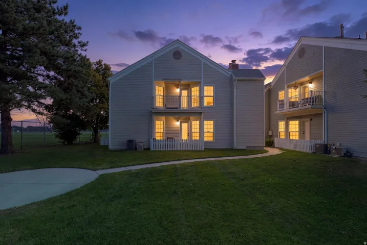 Two-story exterior with siding, individual balconies, separate patio areas, and a concrete pathway