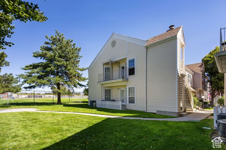 Expansive green lawn, mature trees, white picket fencing, private balcony, and exterior siding