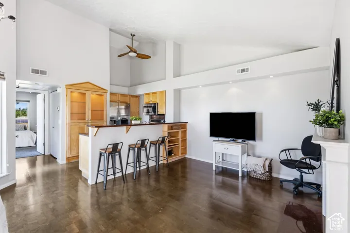 Vaulted ceiling with a ceiling fan, recessed lighting, wood-finish flooring, built-in cabinetry, and integrated stainless steel appliances