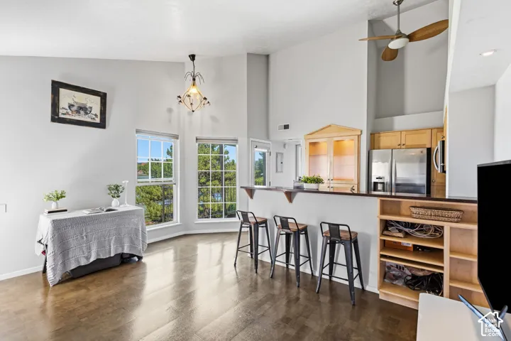 Vaulted ceilings with a ceiling fan, wood-finish flooring, multiple pane windows, a built-in display cabinet, and a breakfast bar with built-in shelving
