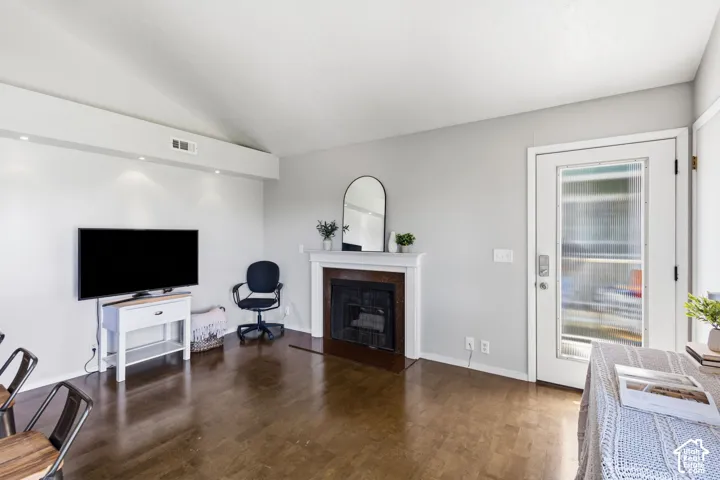 Vaulted ceiling, recessed lighting, wood-finish flooring, fireplace with a wood mantel, and a full-light glass panel door