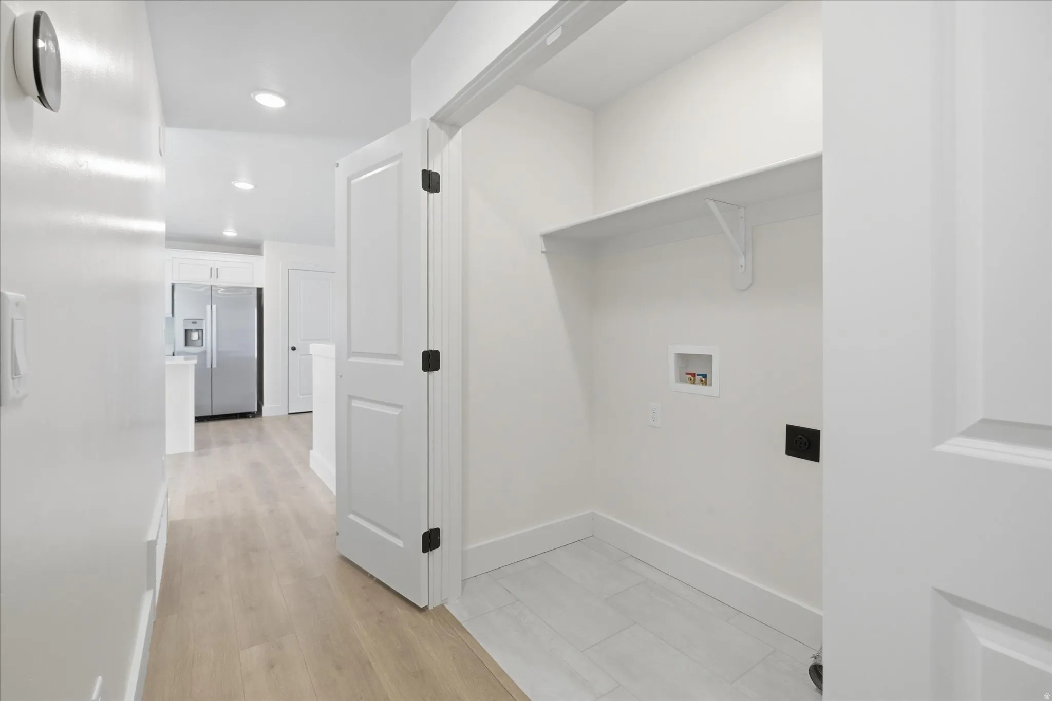 Dedicated utility closet with a built-in shelf, light wood-finish flooring, and recessed lighting