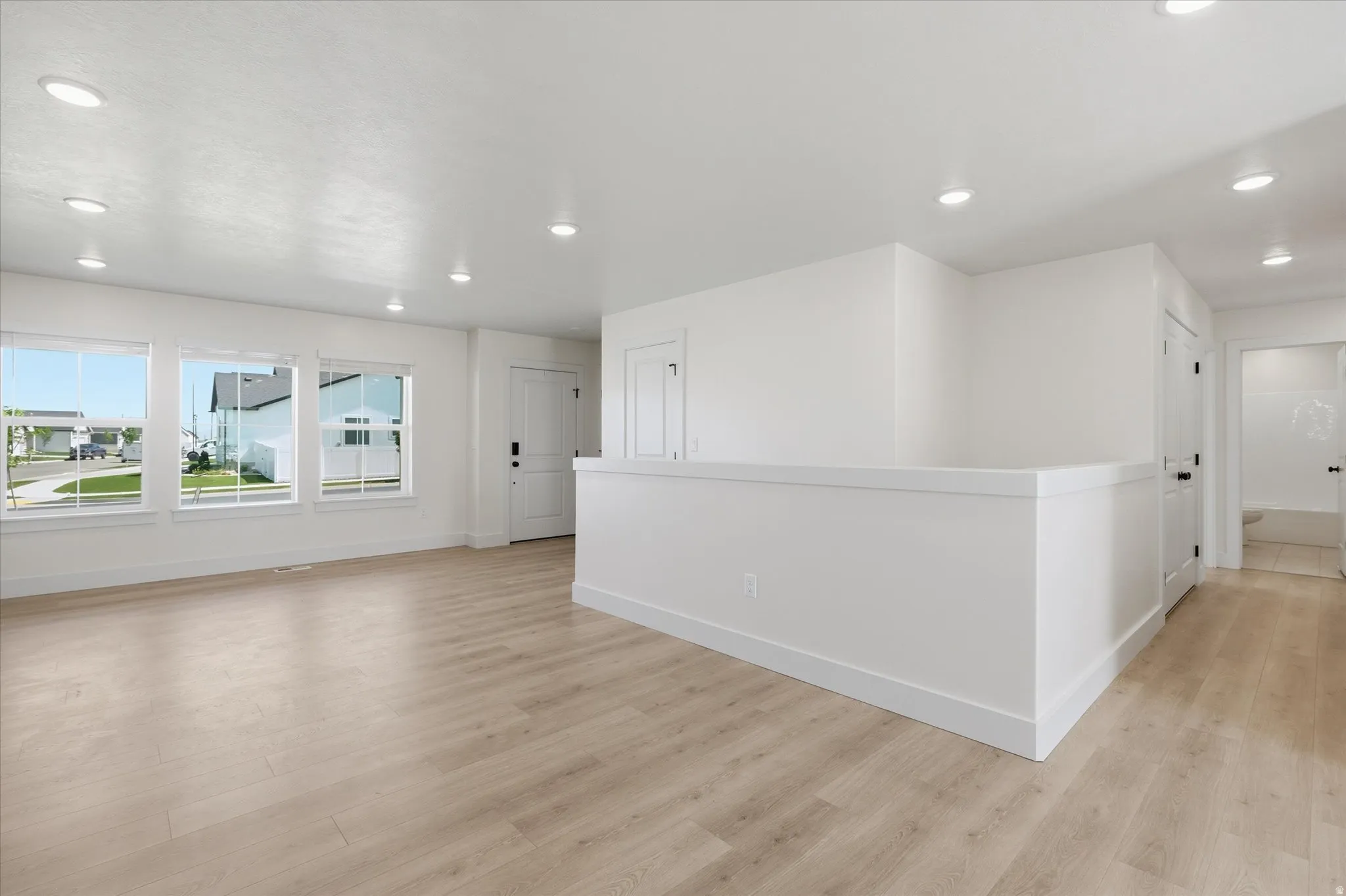 Open-concept living space featuring wood-finish flooring, recessed lighting, and multiple windows