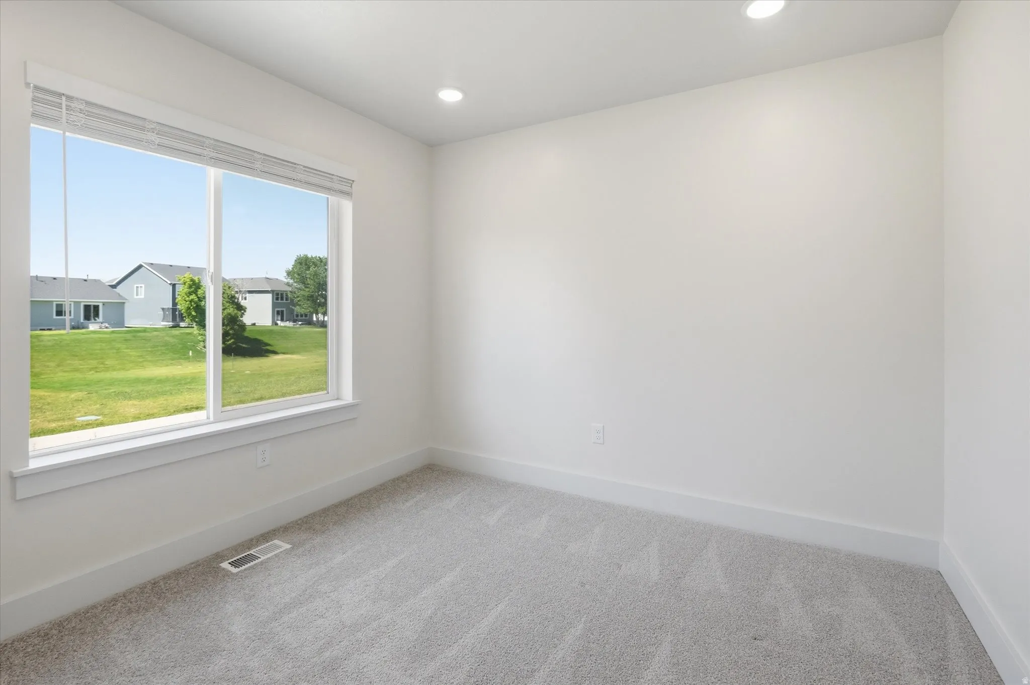 Expansive window with white trim, recessed lighting, neutral wall color, and light-toned carpeting
