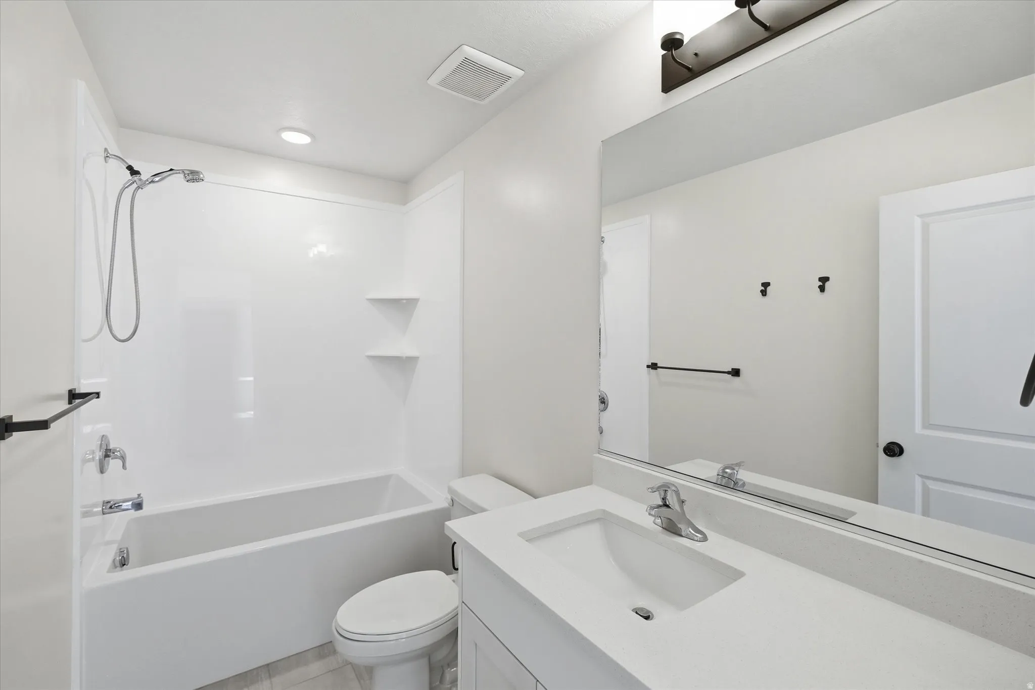 Primary bathroom White vanity with integrated sink, chrome faucet, and expansive mirror