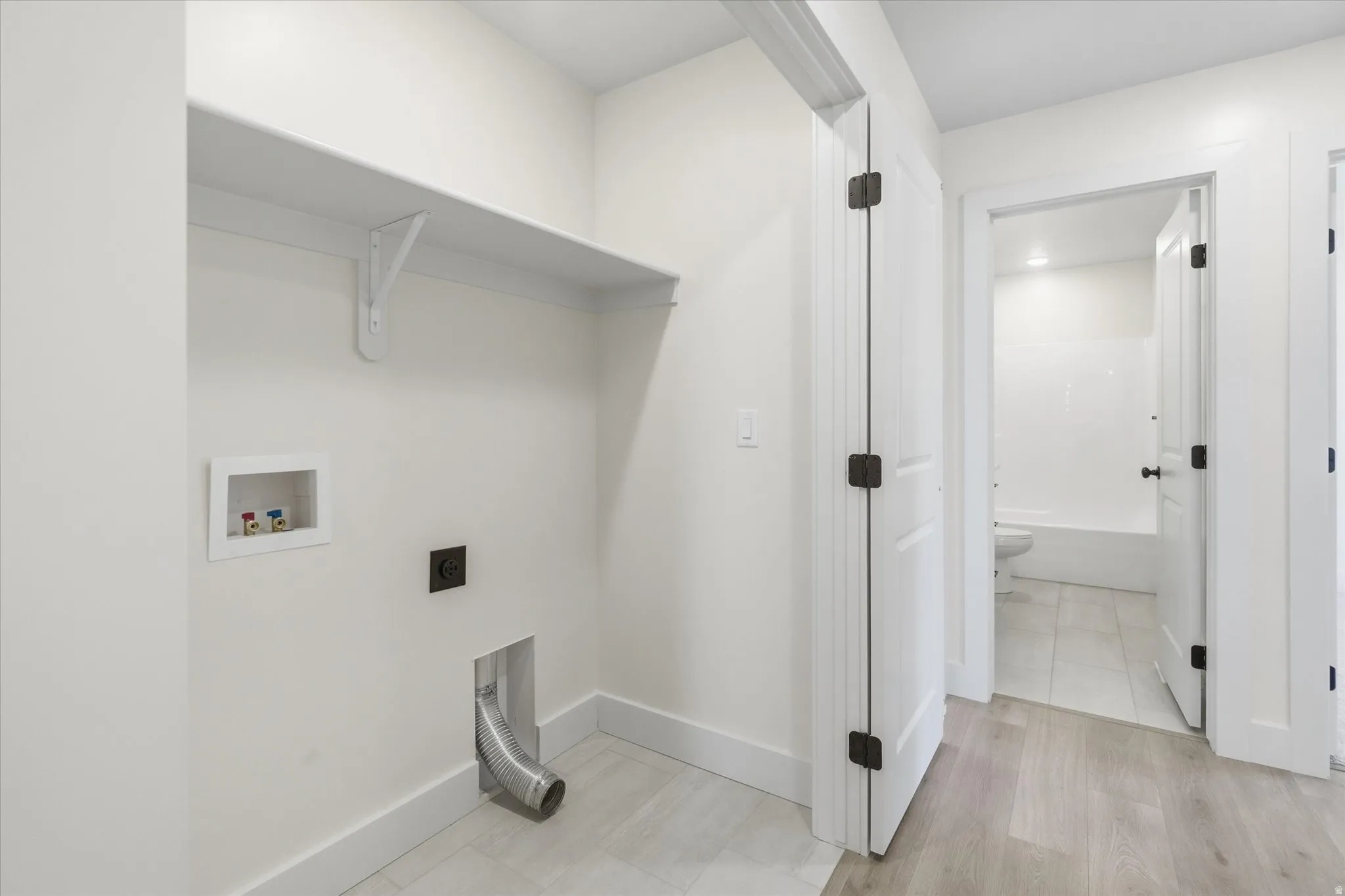 Dedicated laundry area with a utility shelf, wall-mounted water hookups, and a dryer vent