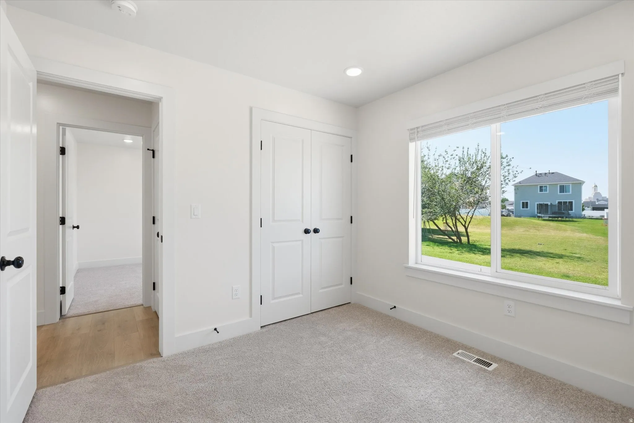 Bright interior with recessed lighting, light-toned carpeting, a built-in closet with double doors, and a large window