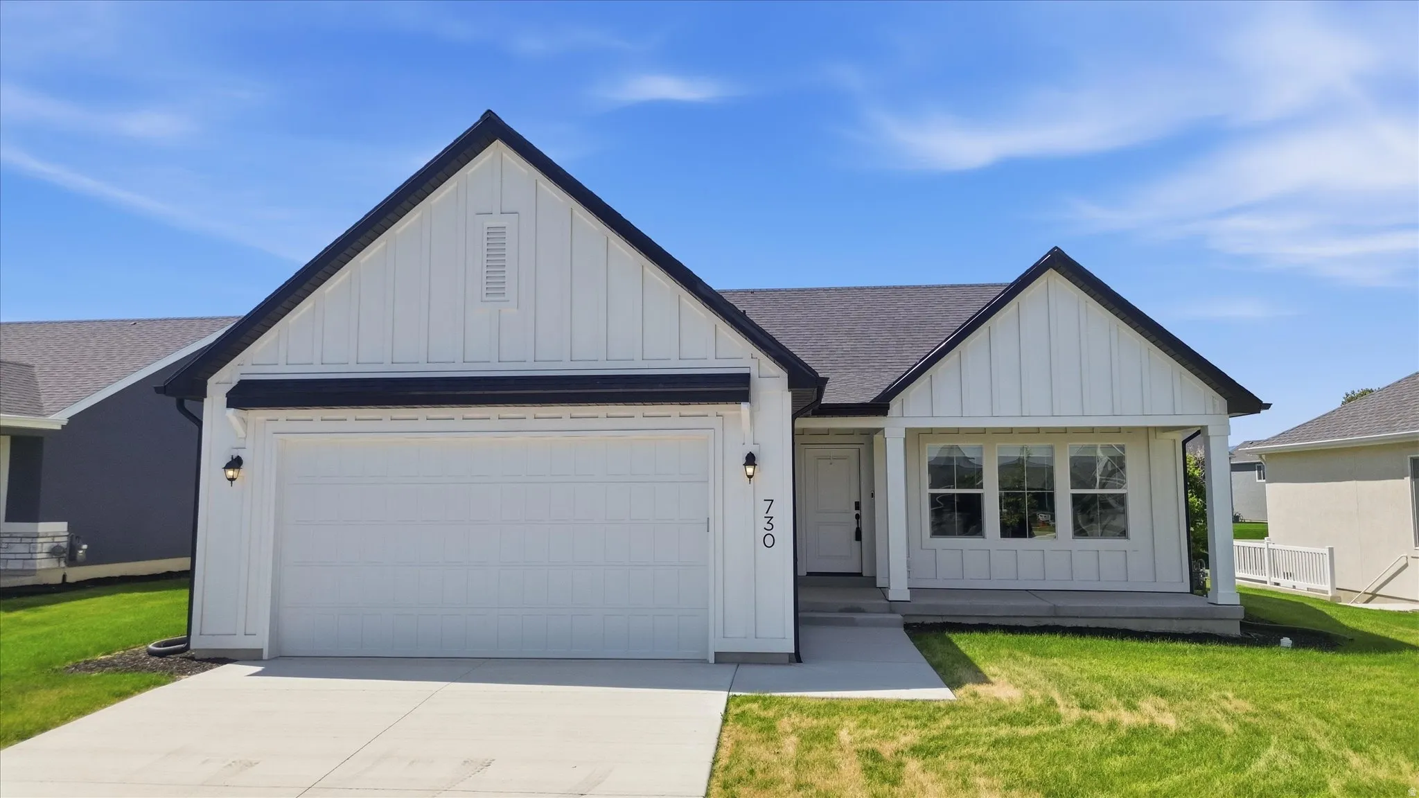 Board and batten siding, dark shingle roofing, attached garage, covered entryway, and concrete driveway