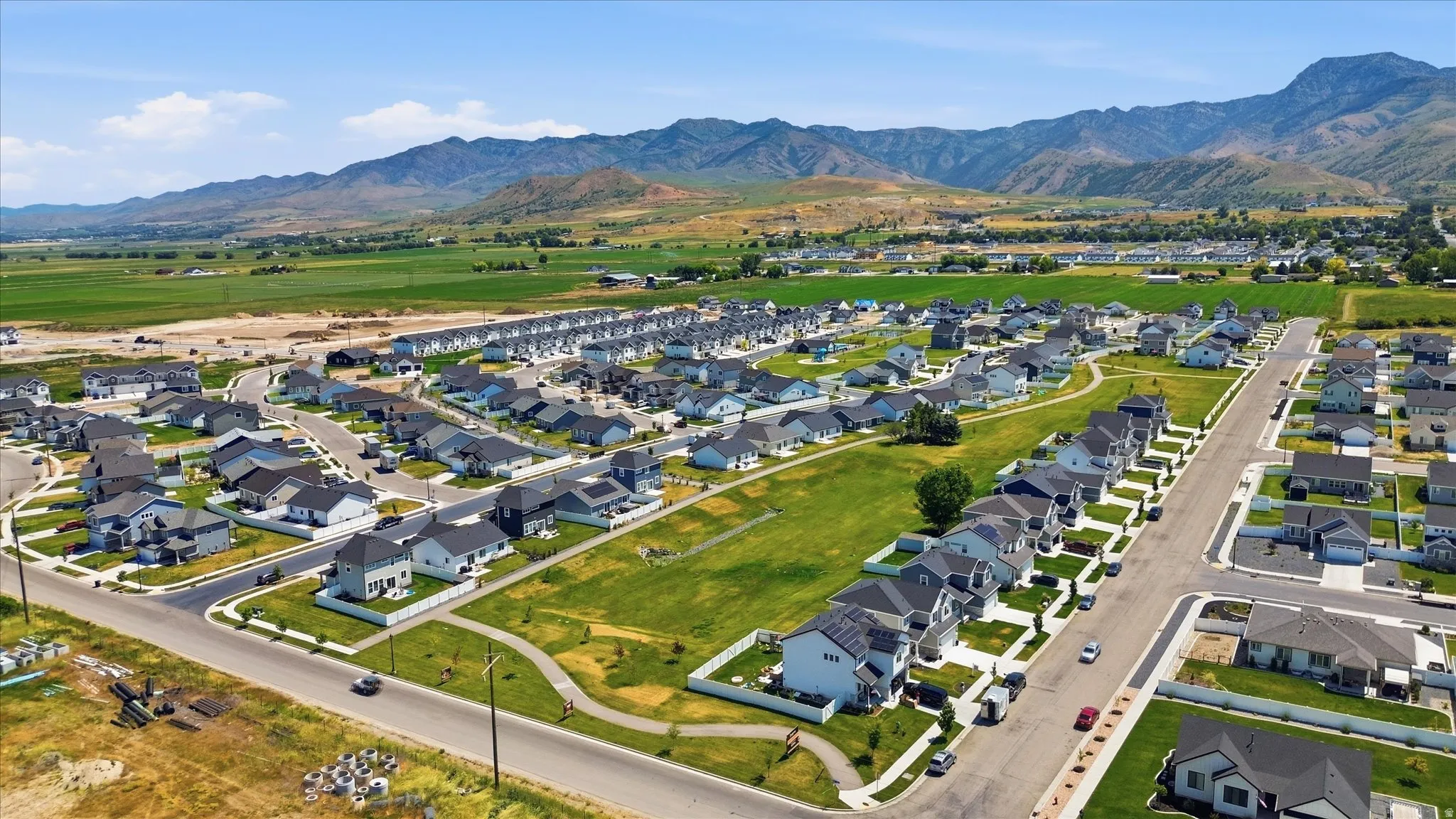 Developed residential community with uniform architectural styles, mountain backdrop, paved streets, and green spaces