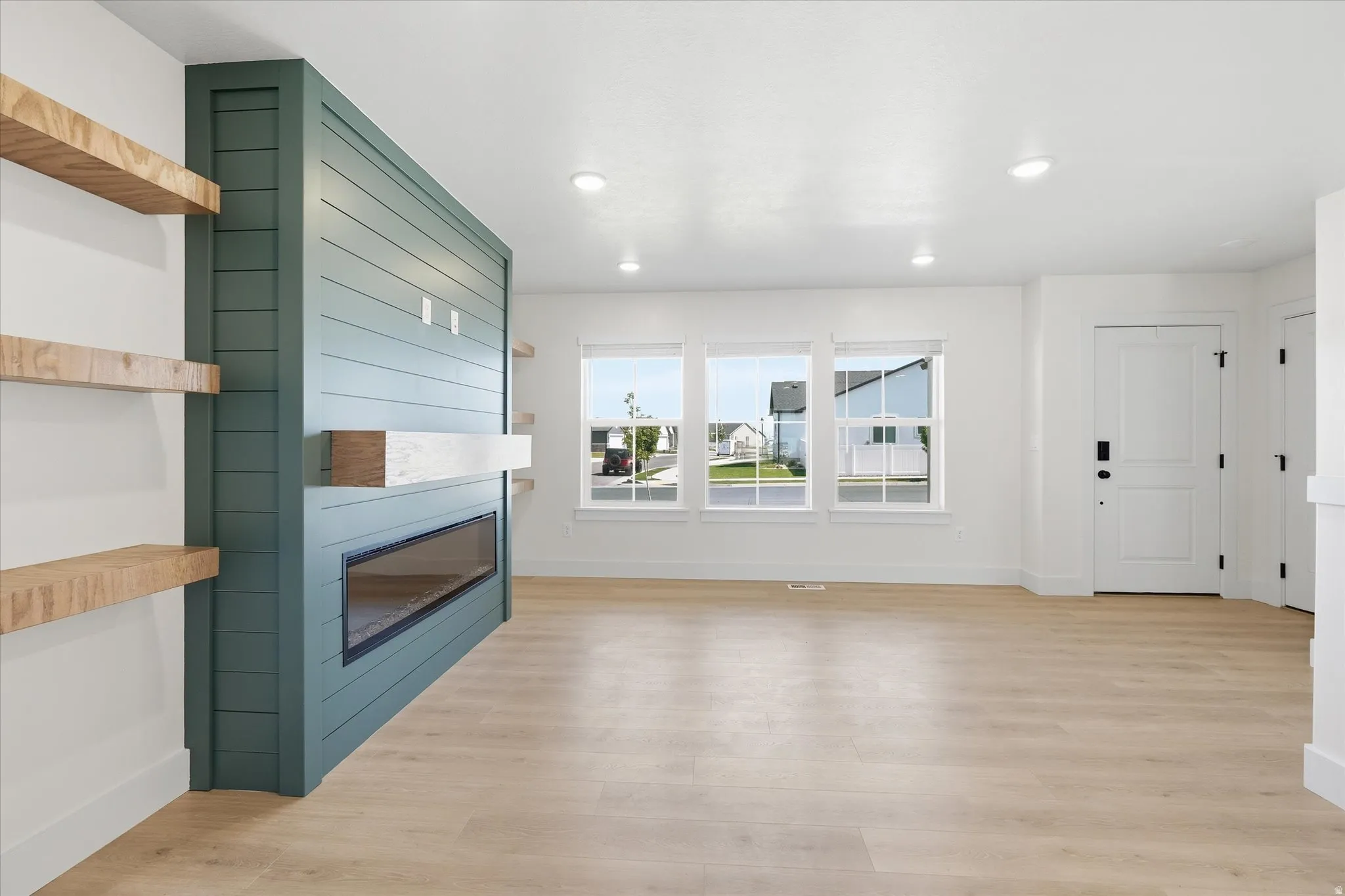 Recessed lighting, wood-finish flooring, a linear fireplace, and a white interior door with black hardware