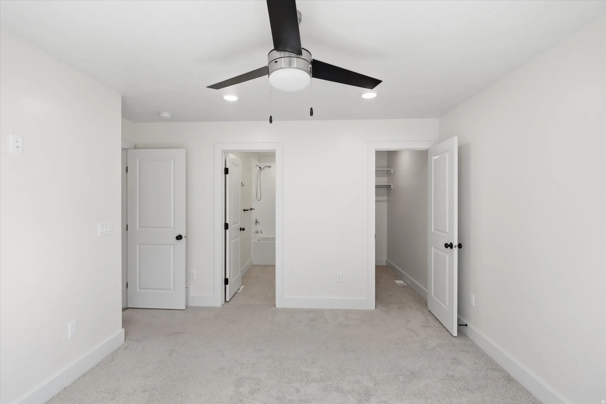Primary bedroom Wall-to-wall carpeting, modern ceiling fan with integrated lighting, recessed lighting, white interior doors with black hardware, and a built-in closet system