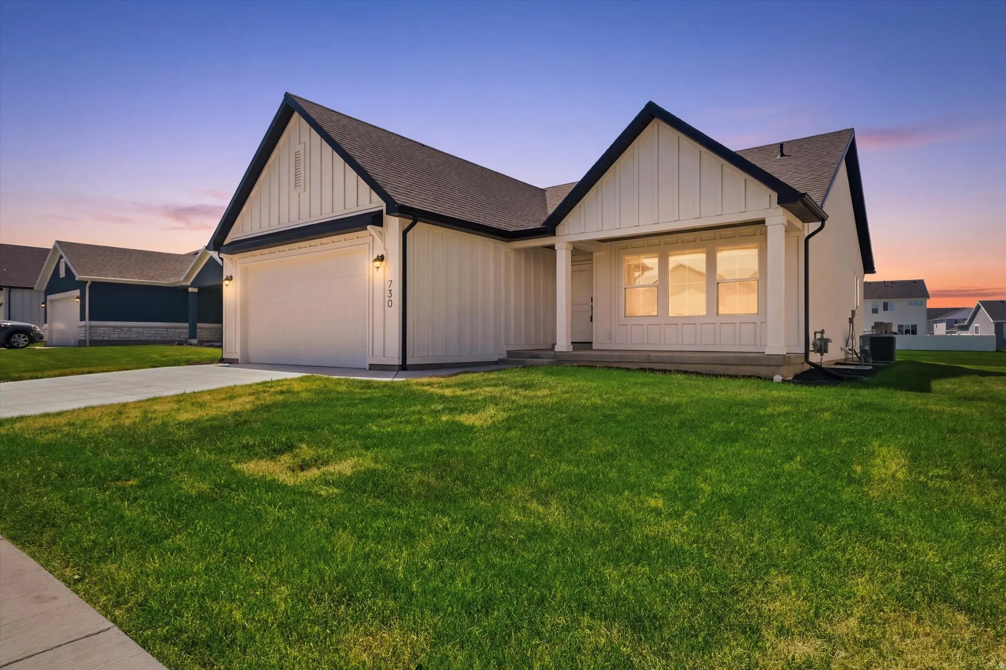 Modern farmhouse exterior with white vertical siding, black trim, a covered porch, a two-car garage, and a concrete driveway