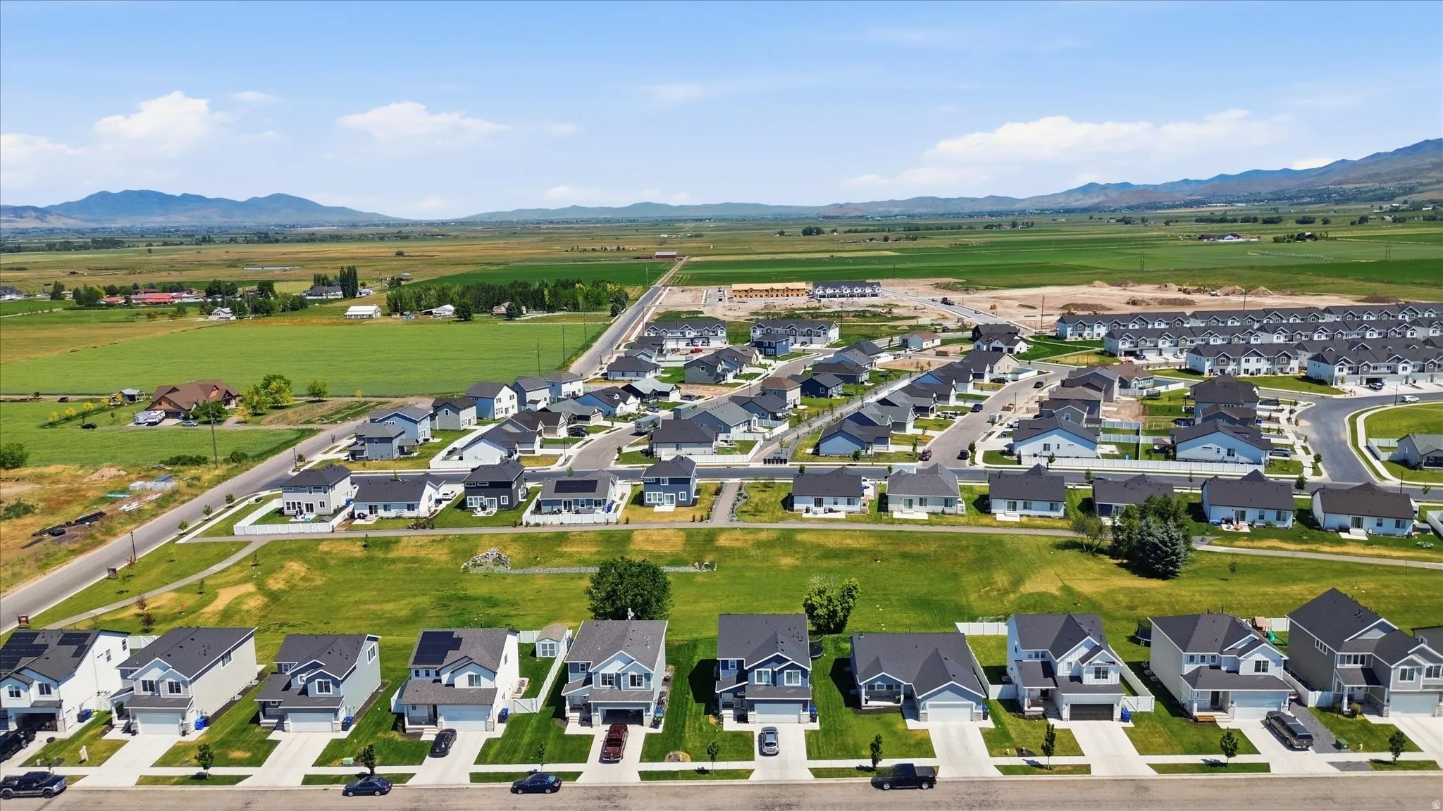 Expansive residential development featuring multiple detached homes, paved streets, and green spaces