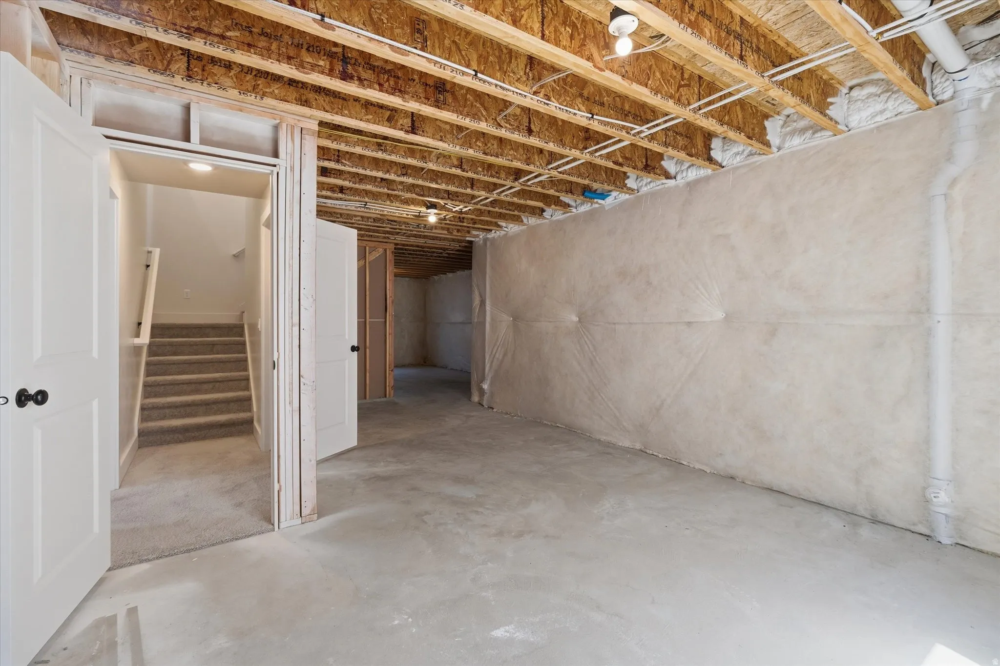Unfinished basement with concrete flooring and exposed ceiling joists