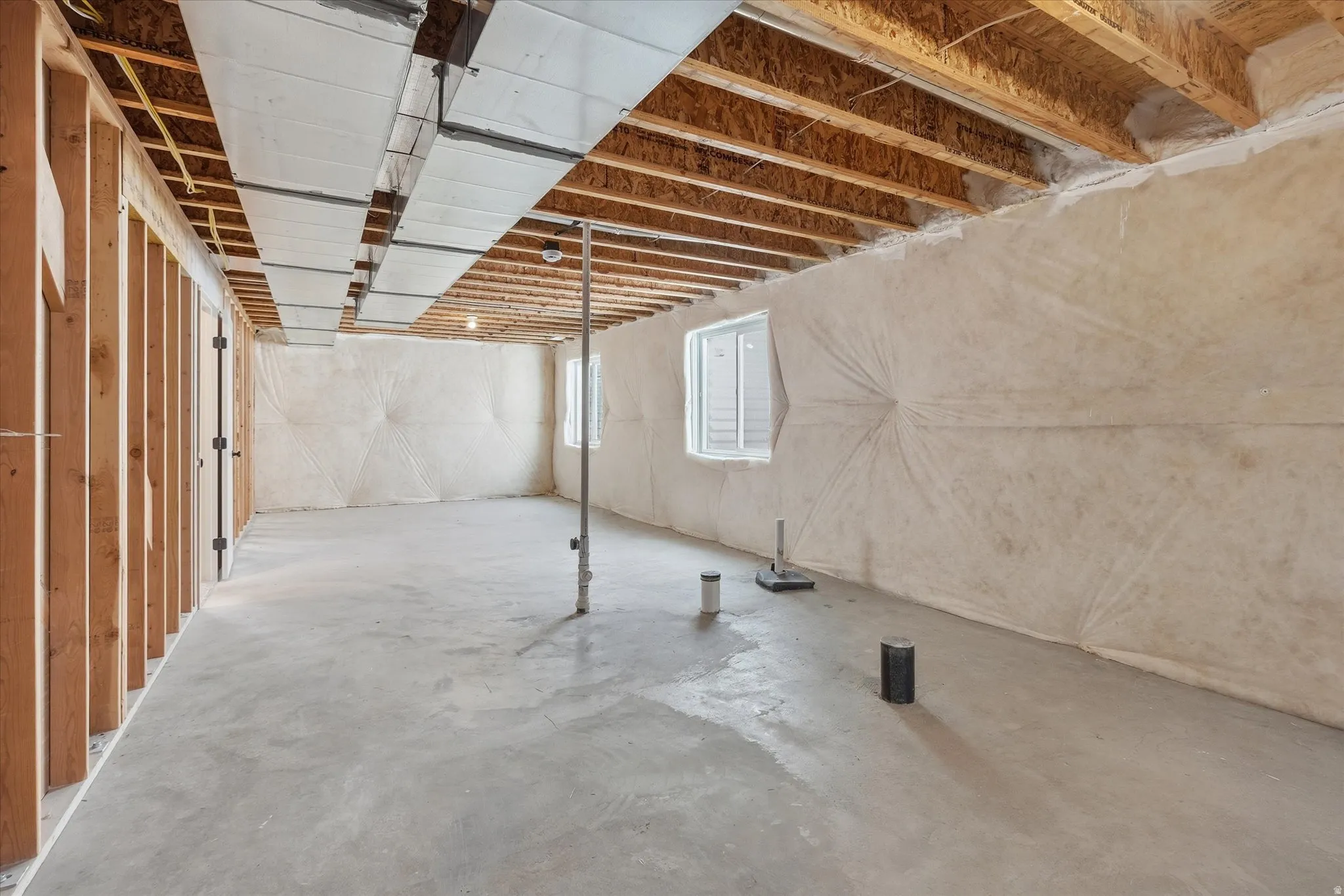 Unfinished basement featuring exposed wood joists, concrete flooring, and framed interior walls