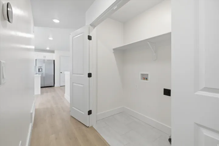Dedicated utility closet with a built-in shelf, light wood-finish flooring, and recessed lighting