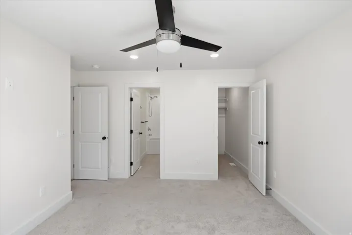 Primary bedroom Wall-to-wall carpeting, modern ceiling fan with integrated lighting, recessed lighting, white interior doors with black hardware, and a built-in closet system
